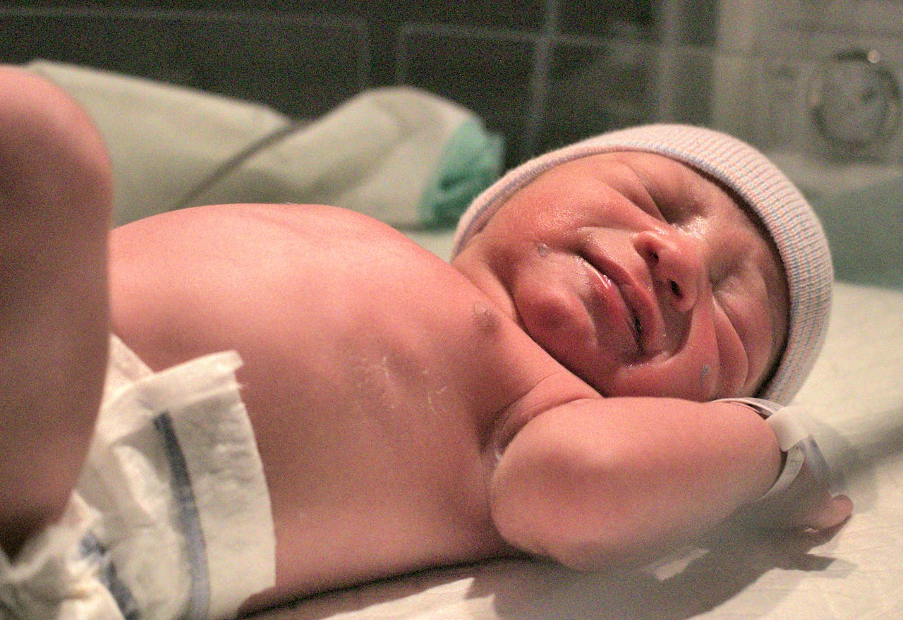 A newborn baby resting peacefully on the hospital bed shortly after birth.